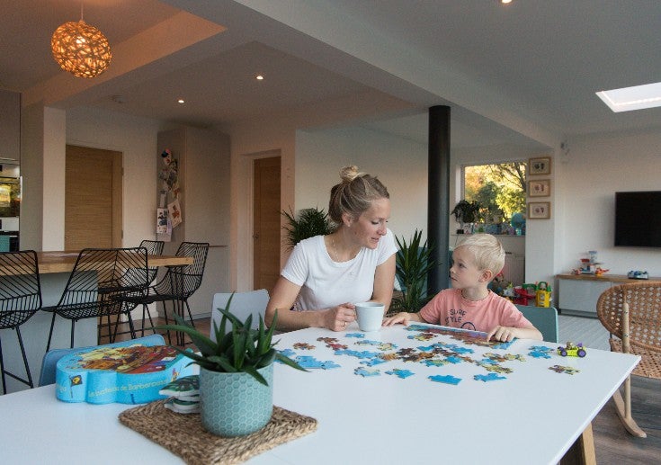 Mother and son completing a jigsaw together at the kitchen table. 