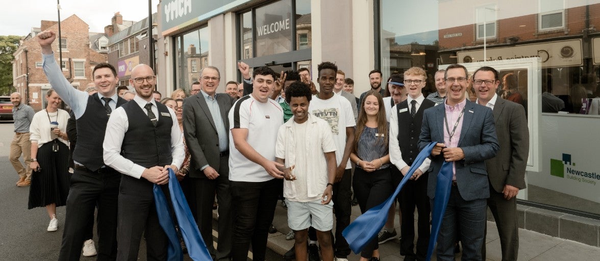 A group of Newcastle Building Society colleagues and members of YMCA North Tyneside stood outside of the YMCA North Tyneside building, getting ready for a ribbon cutting.