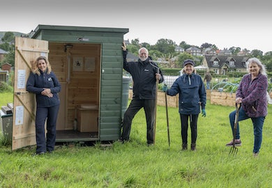 Four people pose outside an eco loo in Wooler