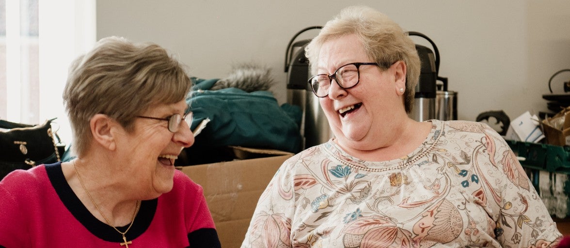 Two members of Fenham Association of Residents looking at each other and laughing.