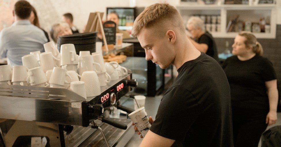 A barista preparing a coffee at a coffee machine. 