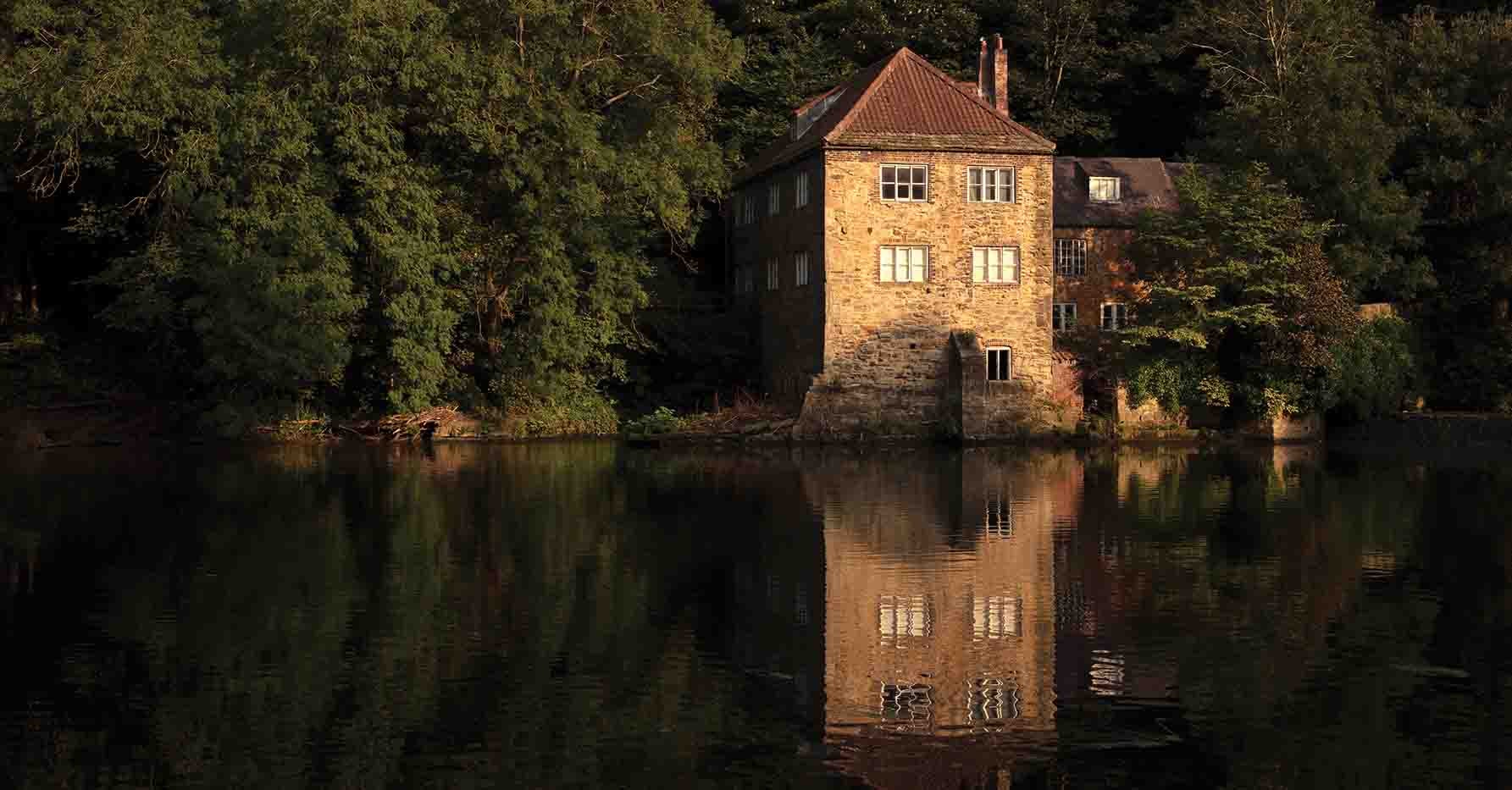 Image of a large building next to Durham's river. 