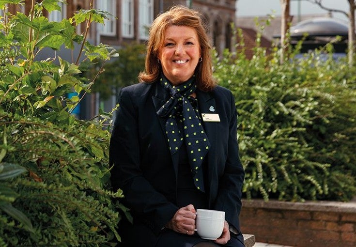 A branch colleague smiles as she drinks a cup of tea.