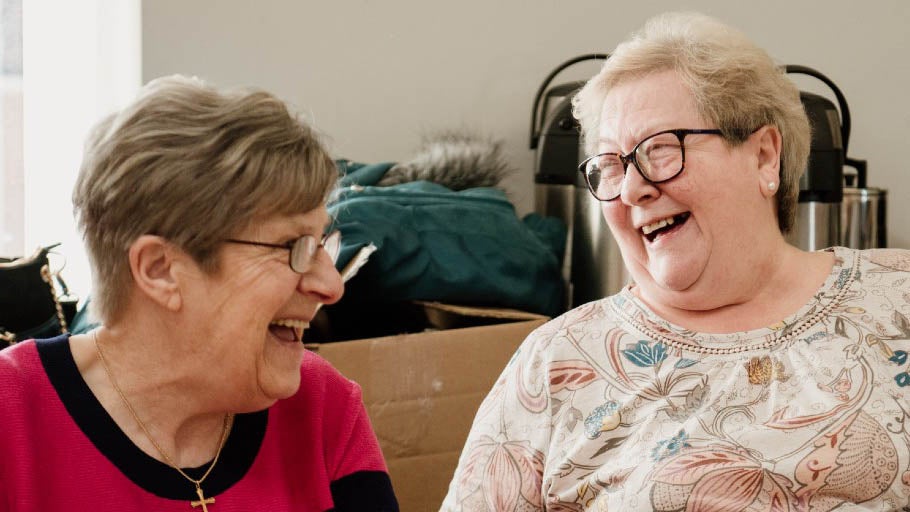 Two members of Fenham Association of Residents looking at each other and laughing.