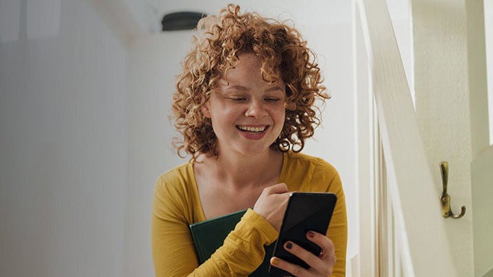 A young adult girl using her mobile phone smiling. 