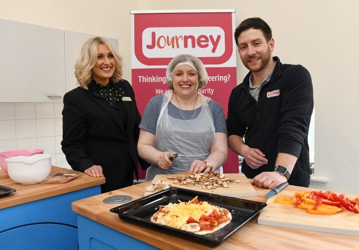 Two women and a man prepare some food.