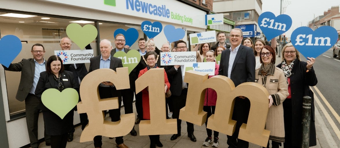 A group of people outside of a Newcastle Building Society branch holding up signs that say 