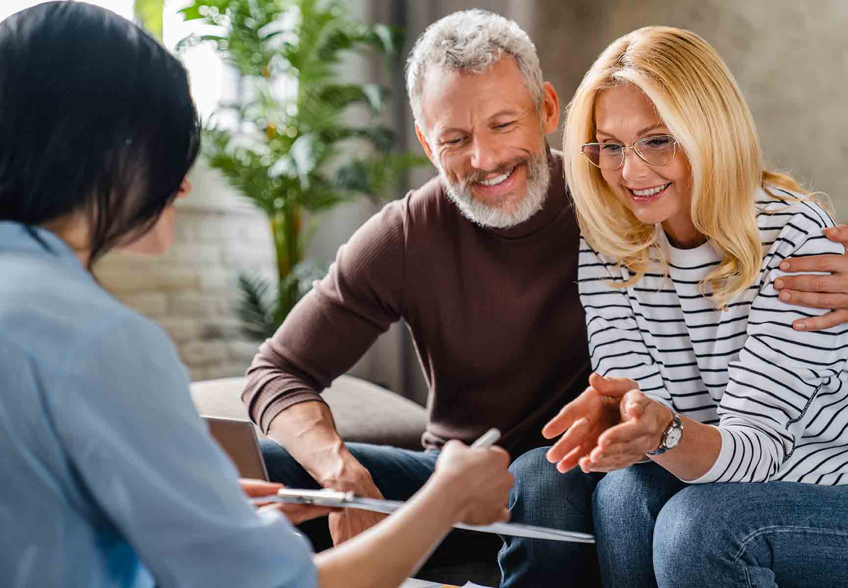 A couple sat smiling with an adviser 