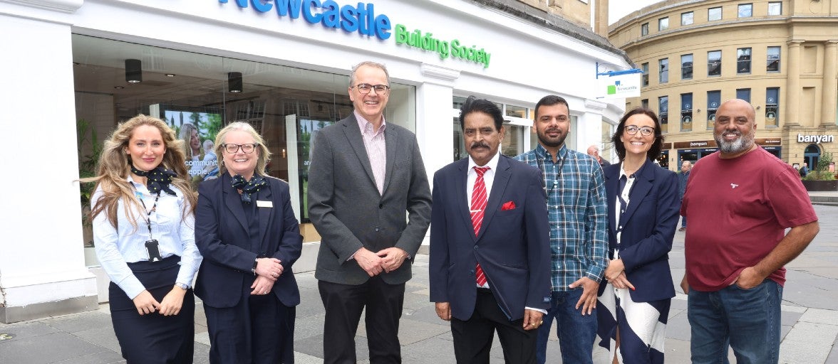A group of people standing in front of the Newcastle Building Society Monument branch.