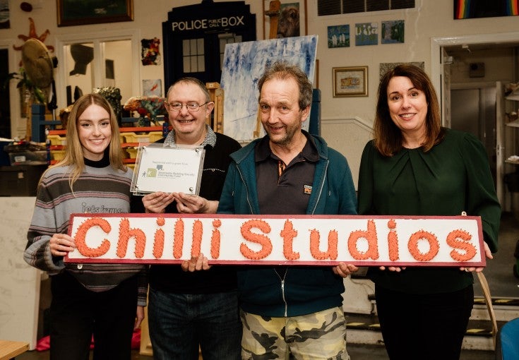 Members of Chilli Studios and our Head of Group Communications, Kathryn McLaughlin, holding a 'Chilli Studios' sign and smiling for the camera.