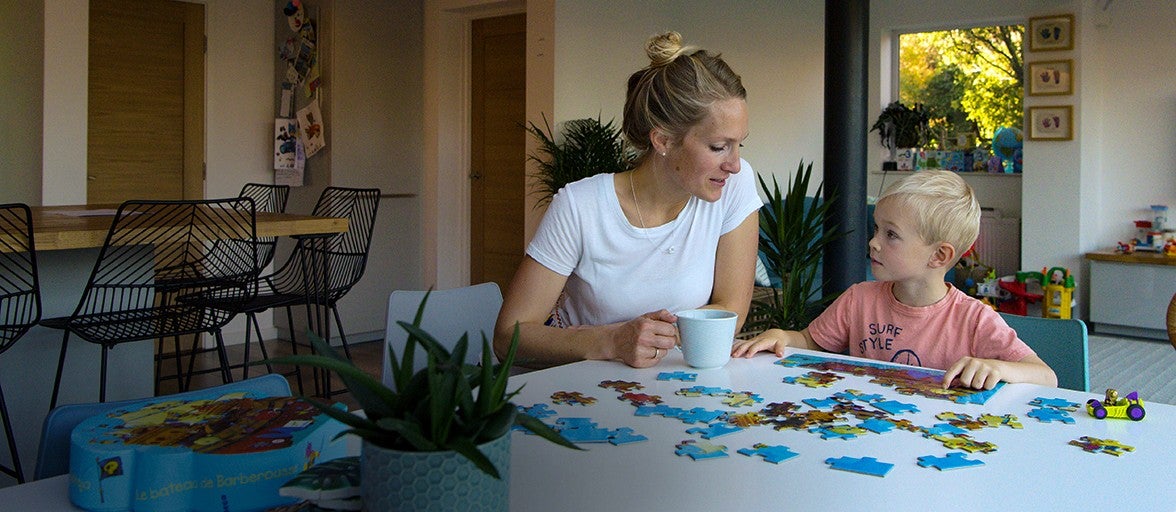 A young mother does a jigsaw in her home with her son