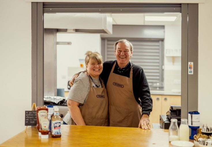 Two members of St Martin's stood together in the kitchen, smiling and posing for the camera.