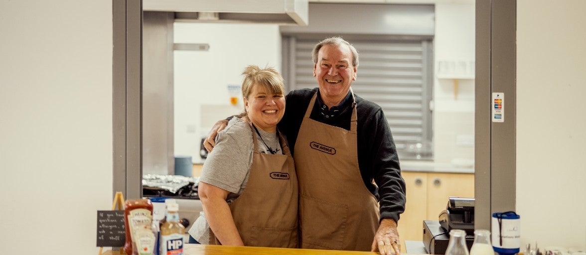 Two members of St Martin's stood together in the kitchen, smiling and posing for the camera.