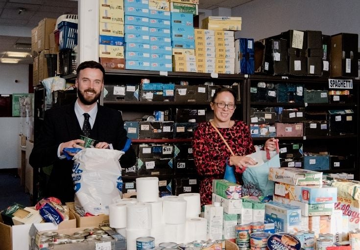 Two people bagging items as part of the Church Together foodbank project