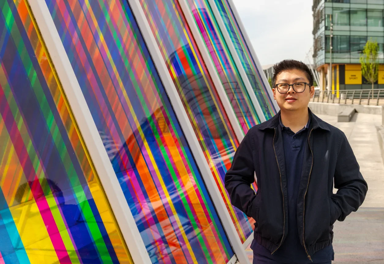 A man standing in front of a colorful glass wall in Salford.