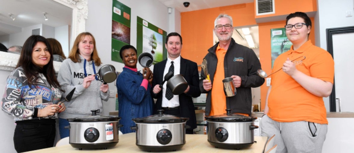 A group of people with slow cookers and kitchen equipment.
