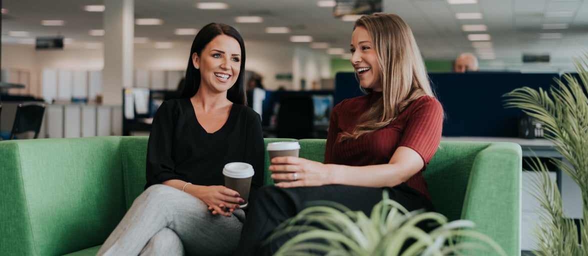 Two colleagues with coffee sat on a sofa in the Newcastle Building Society Head Office