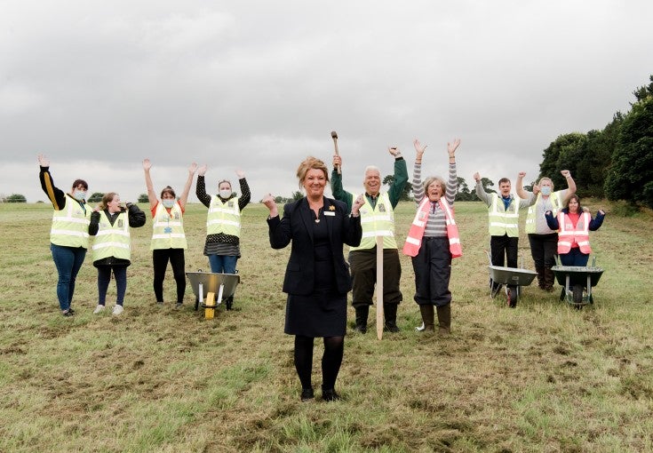 A group of people in hi-vis jackets celebrating in a field