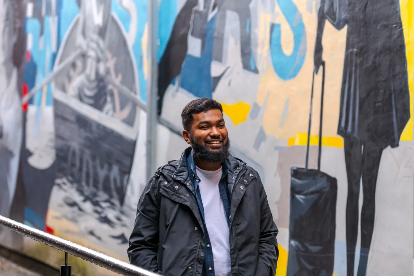 A man standing in front of a mural in Manchester