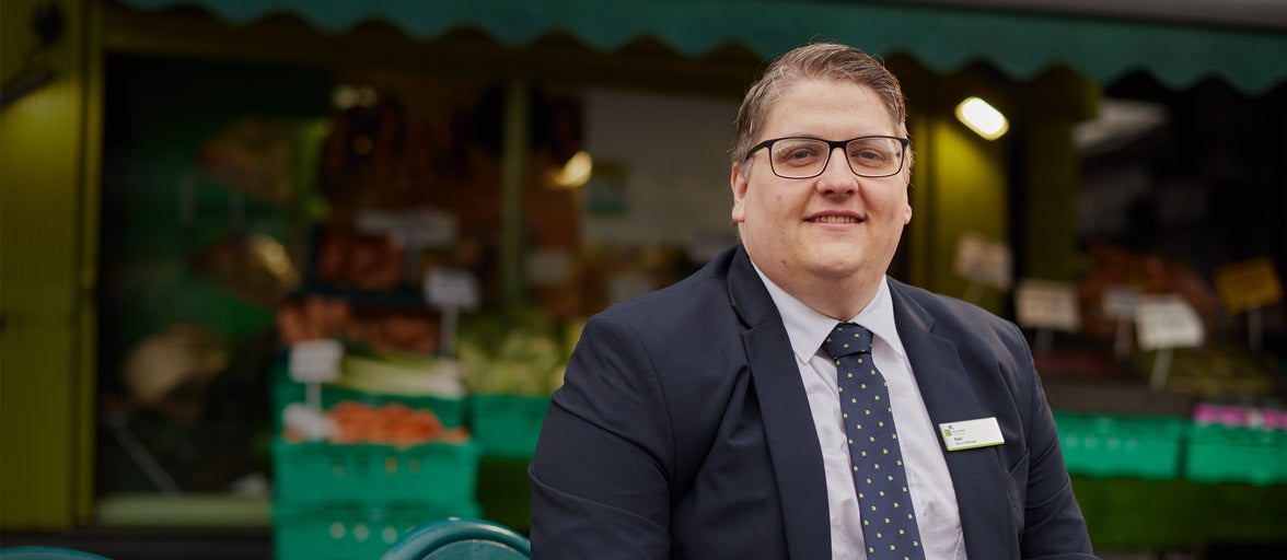 Whitley Bays Branch Manager, Neil, sat outside a fruit and vegetables market. 