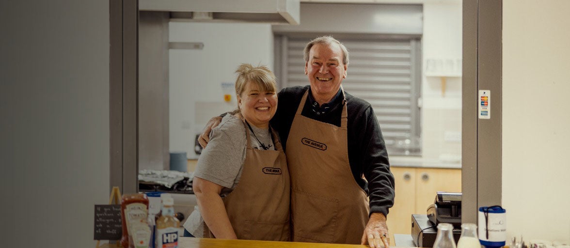 Two members of St Martin's stood together in the kitchen, smiling and posing for the camera.