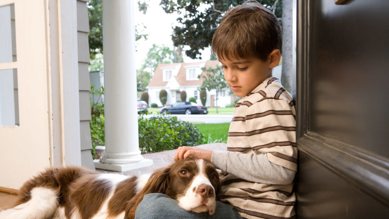 Boy sitting in doorway with dog.
