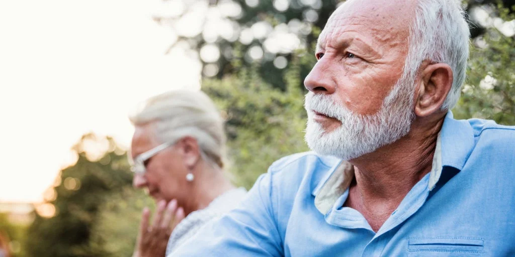 Elderly couple outside as man looks off to the distance