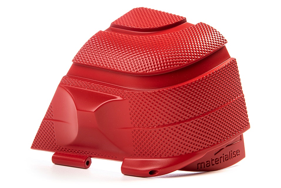 The corner of a red, textured 3D-printed Samsonite suitcase made using stereolithography.