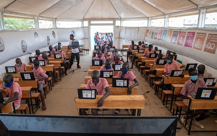 Children sitting at desks in a Maggie Shelter on computers