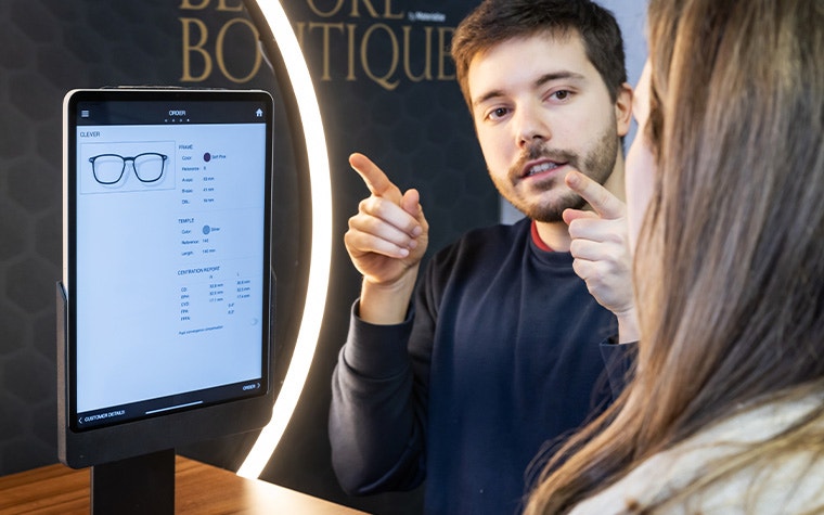 A man and a woman talking to each other in front of an iPad running the Eyewear Fitting Suite.