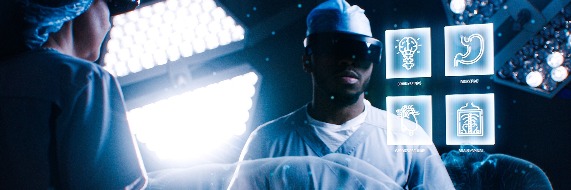 A male and female surgeon are in an operating room wearing augmented reality headsets. Floating in front of them are four virtual panels representing "brain and spinal," "digestive," and "cardiovascular" systems.