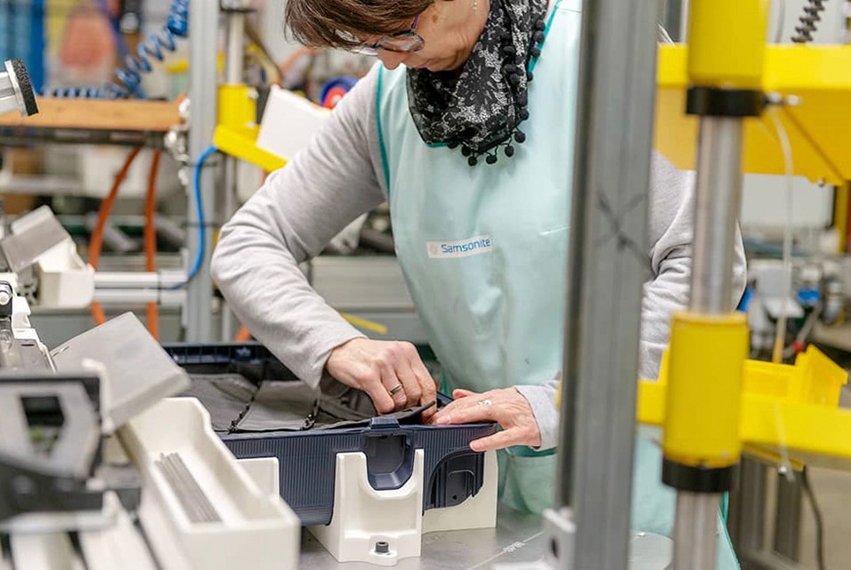 A worker adjusting a piece of the suitcase