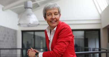 Brigite de Vet-Veithen smiling while leaning on a railing in the Materialise office