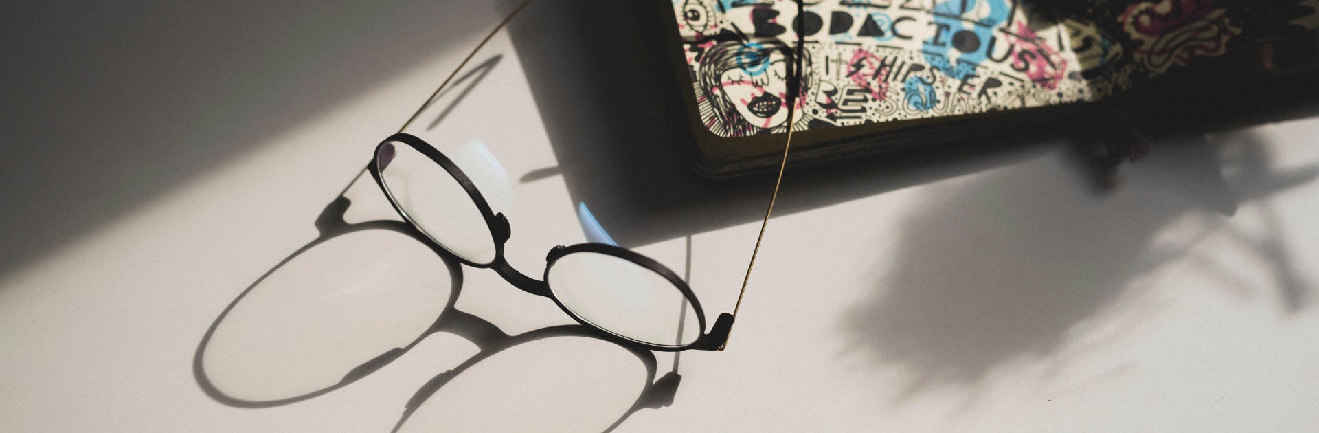 Eyeglasses laying on a design with its shadow extended