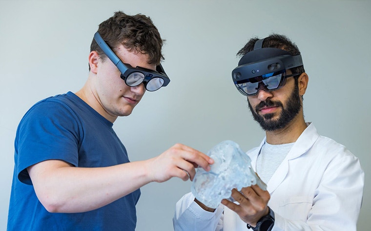 一人はHoloLens、もう一人はMagics LeapのARゴーグルを装着し、解剖模型を見ている二人の男性