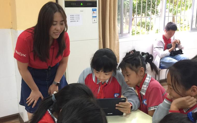 Kids and a teacher looking at a tablet 