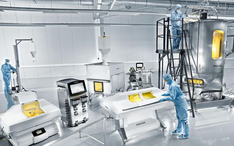 Laboratory workers in full protective gear working on Sartorius equipment.