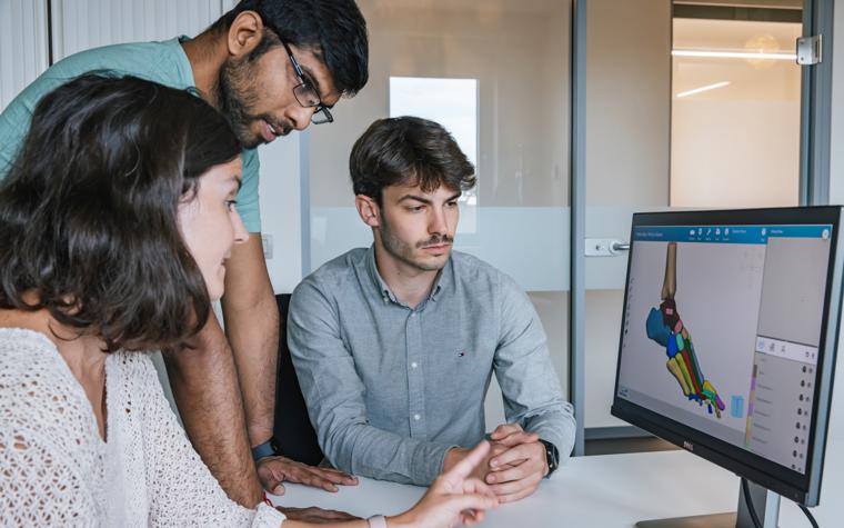 Three people looking at a screen with Mimics Flow Case Management and a segmented image of a foot