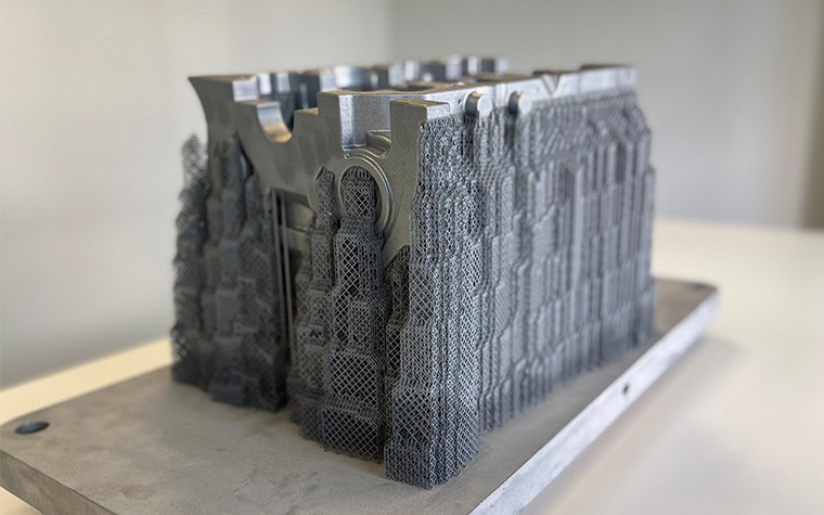 A metal 3D-printed crankcase produced by the BÖLLINGER GROUP sitting on a wooden table.