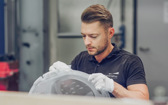 Hombre lijando una pieza impresa en 3D en una planta de producción de Materialise