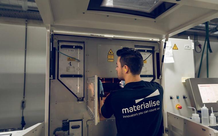 3D printer operator at Materialise looking in the open door of a machine