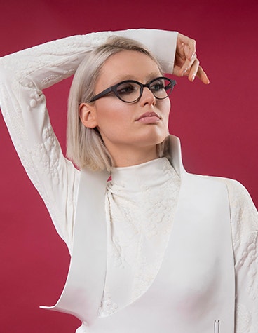 Female model posing with a hand on her head, wearing navy Hoet Cabrio Bi-Color eyeglasses