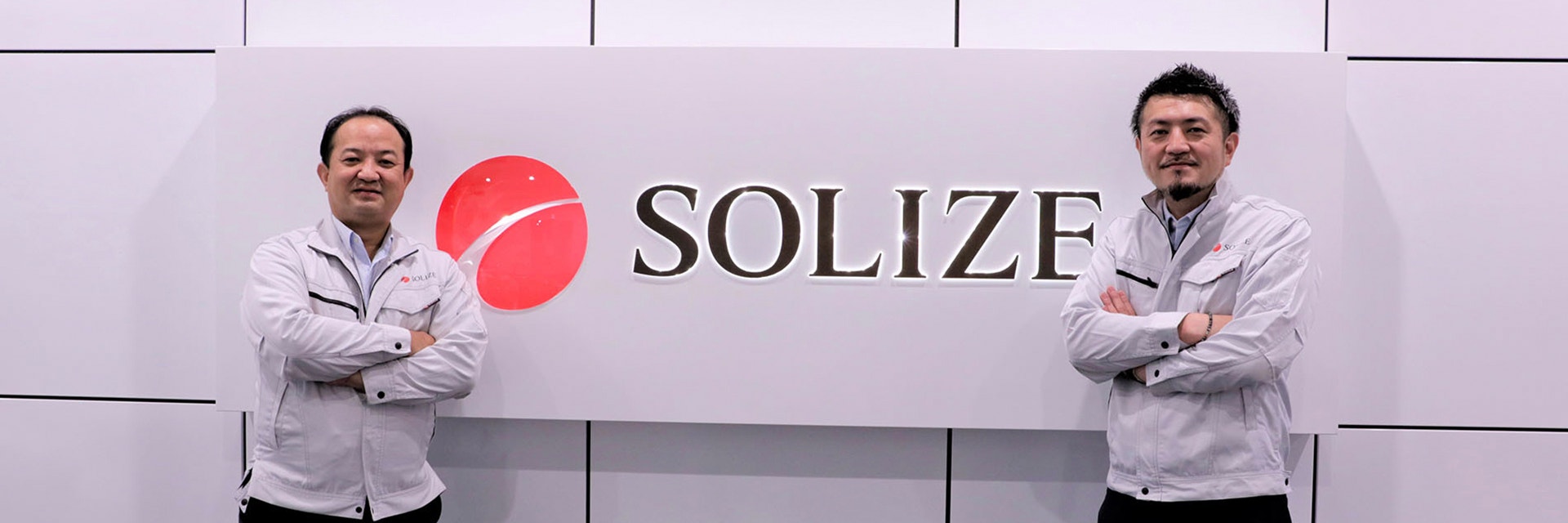 Two SOLIZE team members standing next to a SOLIZE sign.