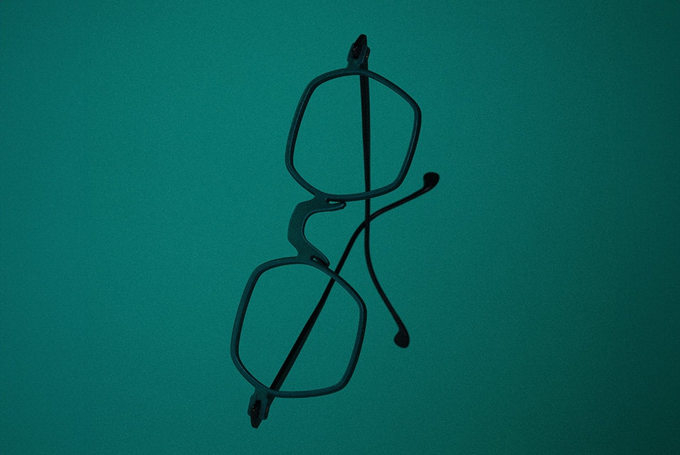 A pair of black 3D-printed Acuitis frames against a green background