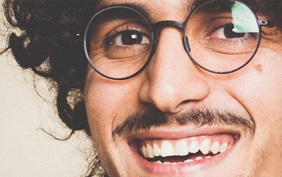Lächelnder Mann mit lockigem Haar und Schnurrbart, während er eine 3D-gedruckte Weareannu-Brille trägt