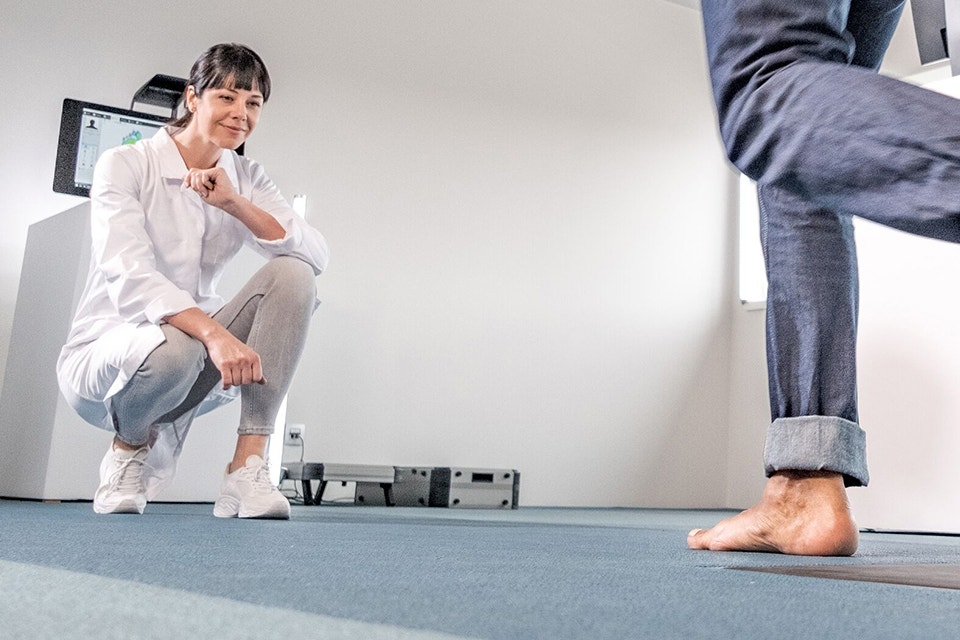 Doctor crouching down to observe a patient running on a footscan