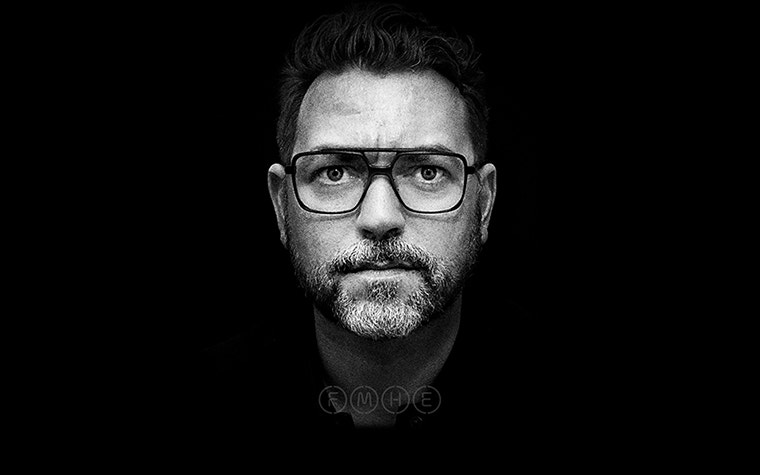 Black and white headshot of man looking directly at camera wearing 3D-printed glasses 