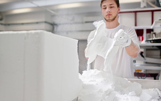 Man removing 3D-printed parts from a powder bed