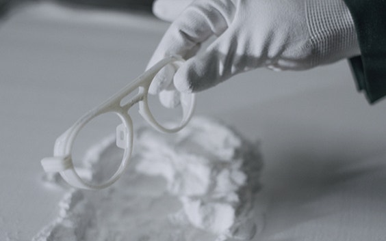 Gloved hands removing 3D-printed Odette Lunettes eyewear frames from a powder bed