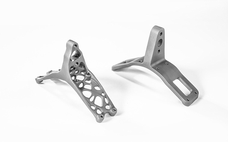 Two titanium brackets side by side. The lightweight bracket called ENDY on the left is based on a generative design and has irregular holes